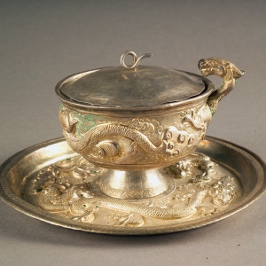 Silver cup and saucer with dragon designs